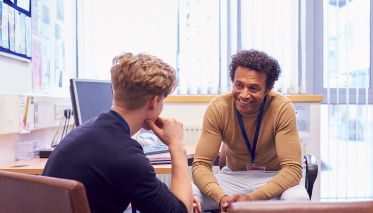 Male teacher and student smiling while talking
