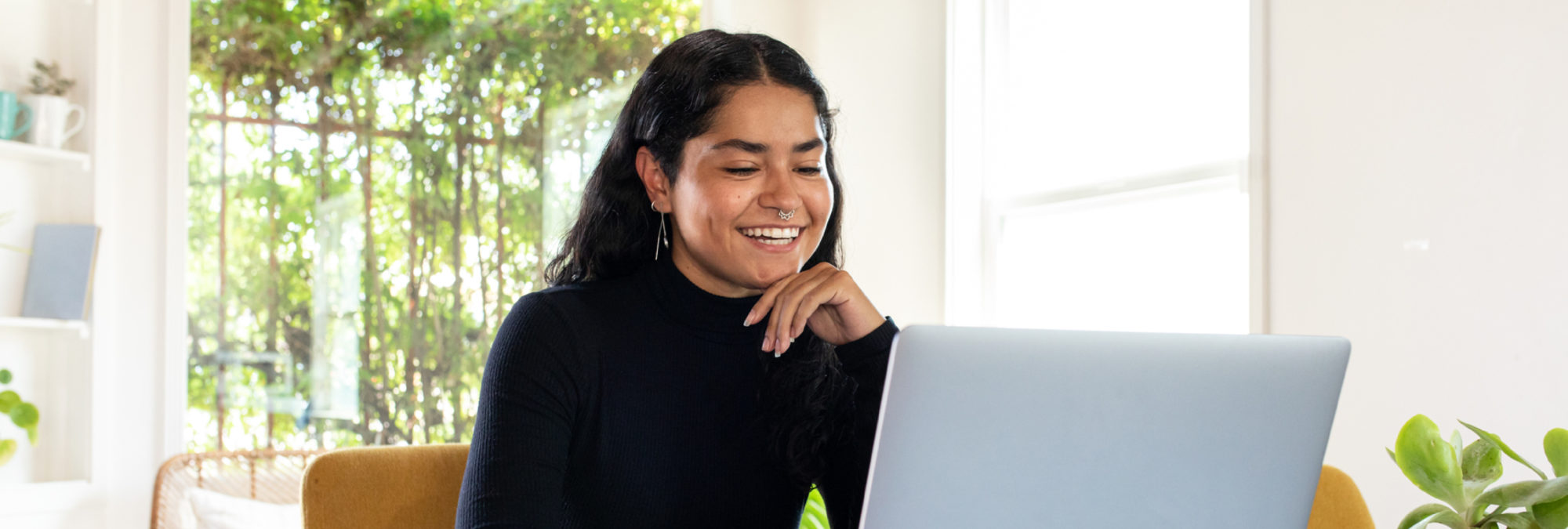 Female student in black sweater smiling at laptop